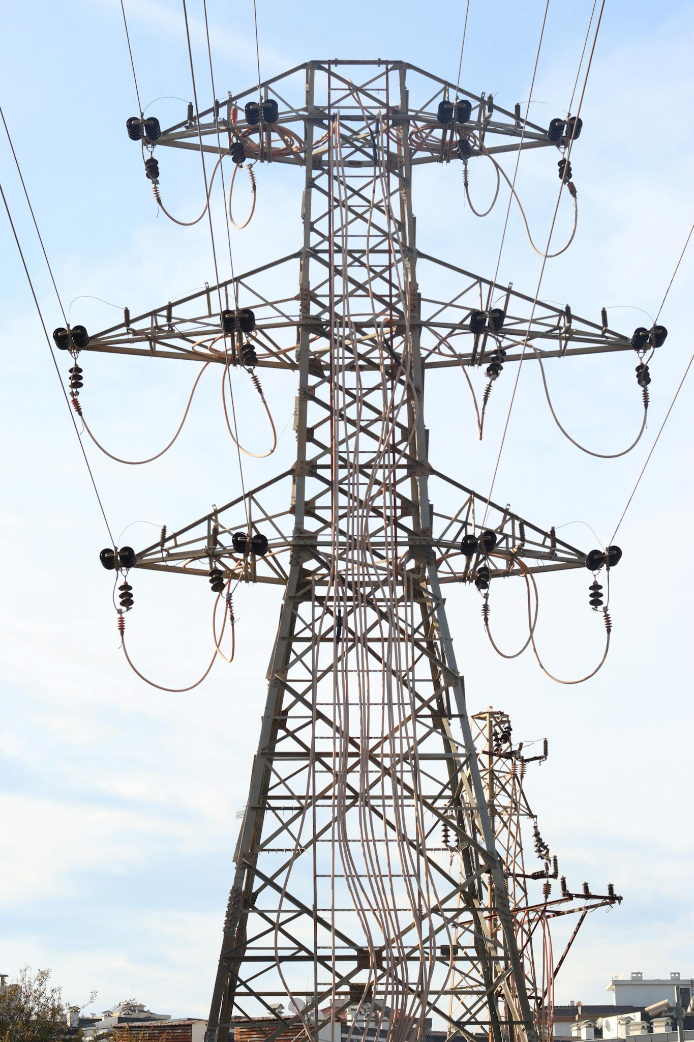 A high voltage electrical transmission tower standing tall against a clear blue sky.
