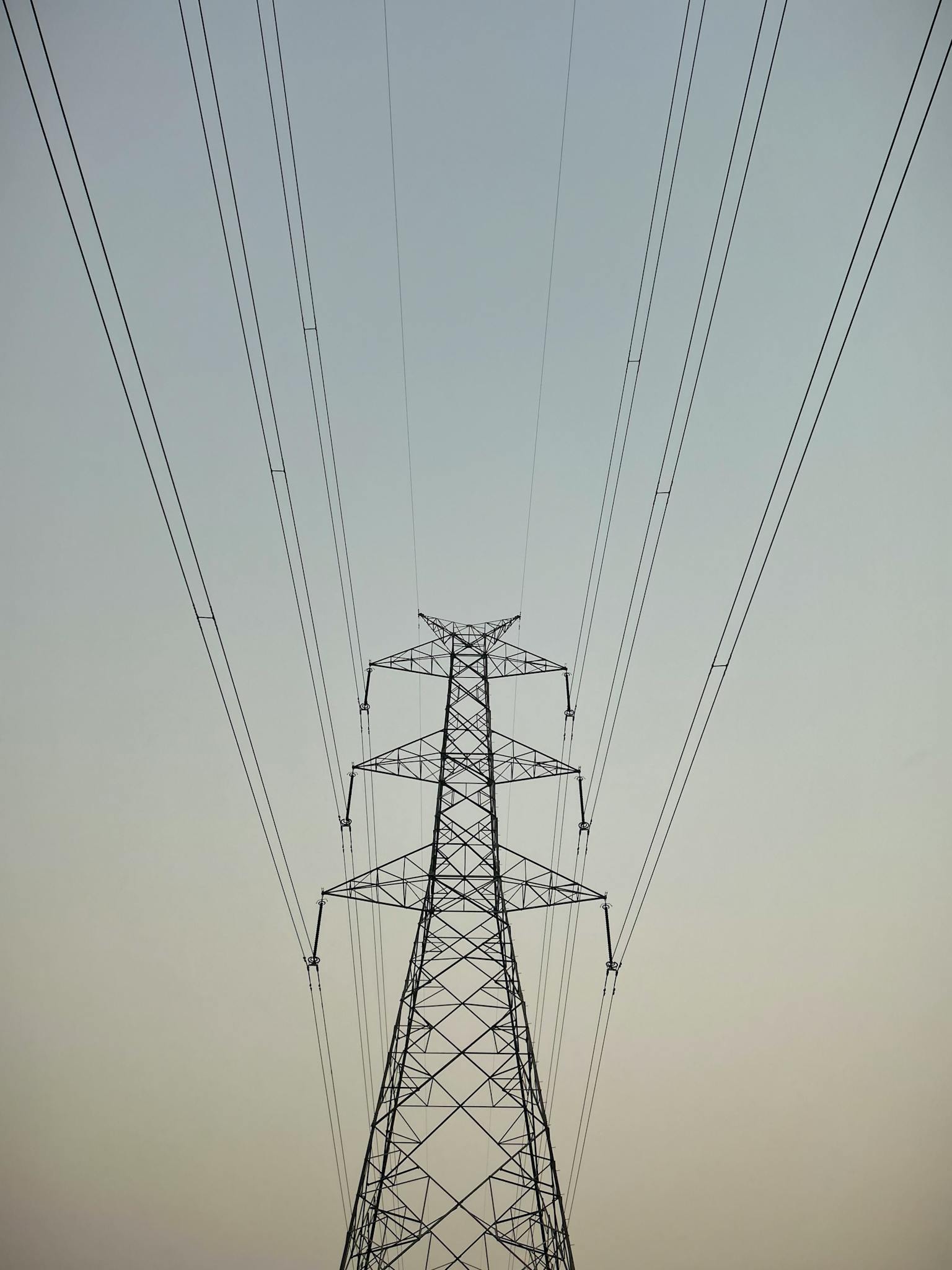 A towering electricity pylon set against a tranquil clear sky, illustrating infrastructure and energy.