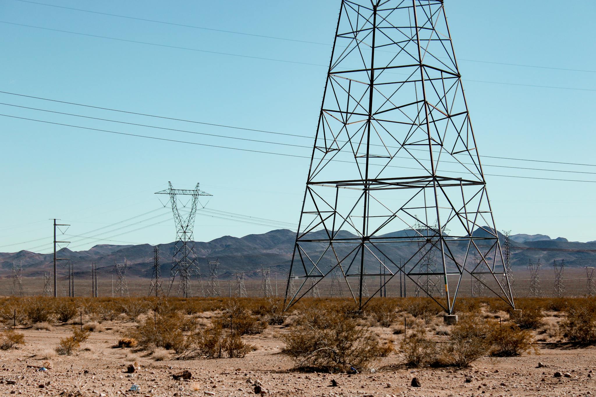 High voltage power lines stand tall in the vast Nevada desert under a clear blue sky.